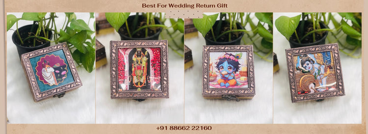 Decorative boxes with artistic designs on a white surface, surrounded by green plants.